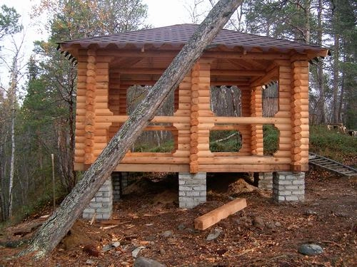 Grill paviljongen har en robust konstruksjon med solide trebjelker. Den har et åpent design, med et solid tak laget av tømmerplanker for å gi beskyttelse mot sol og regn.